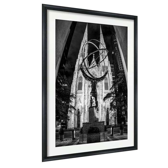A black and white photograph of a large cathedral with a statue in the foreground, framed in a black frame.