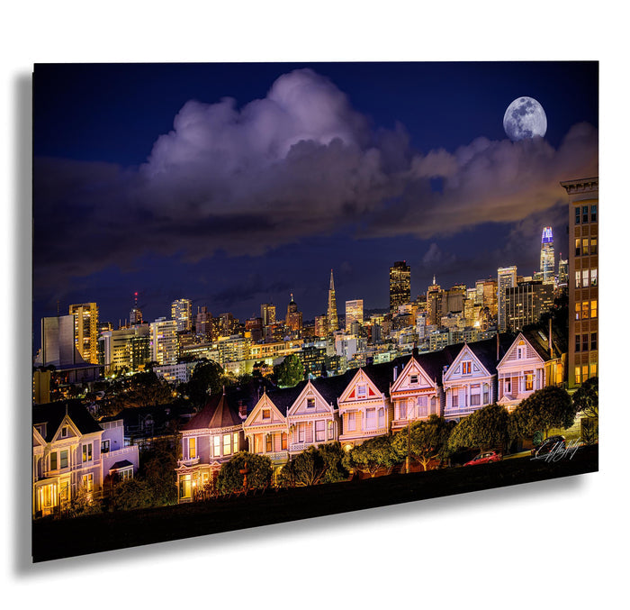 A nighttime cityscape with a full moon and a row of Victorian-style houses in the foreground, with the city's skyscrapers and buildings illuminated in the background.