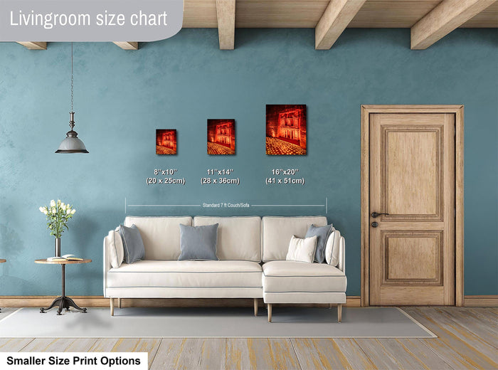 a living room with a white sofa, a wooden door, and a hanging light fixture. There are three framed artworks displayed on the wall, each with a different size and frame. The living room appears to be well-decorated and spacious.