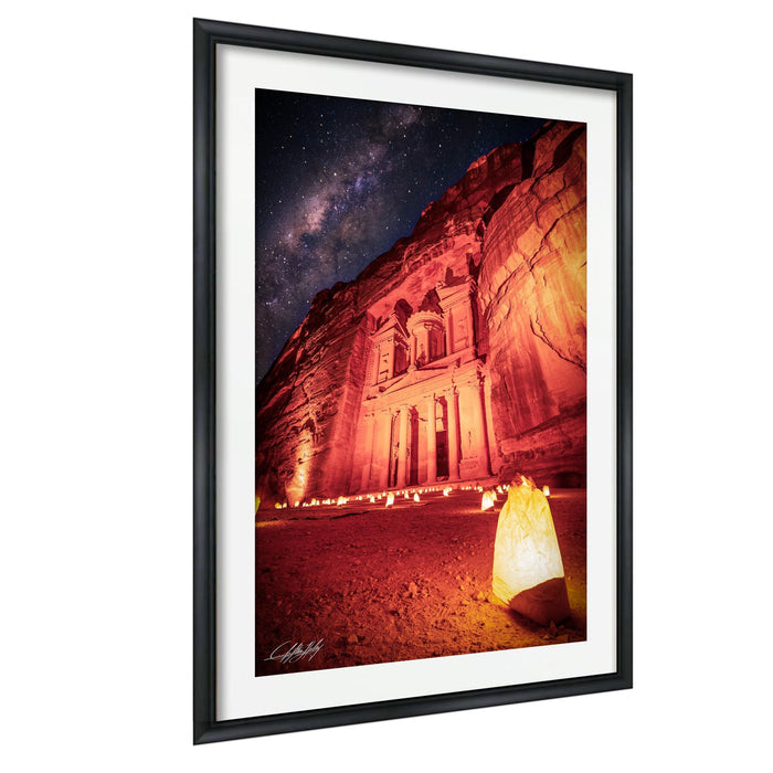 a large, ancient building illuminated by warm, glowing lights against a starry night sky.