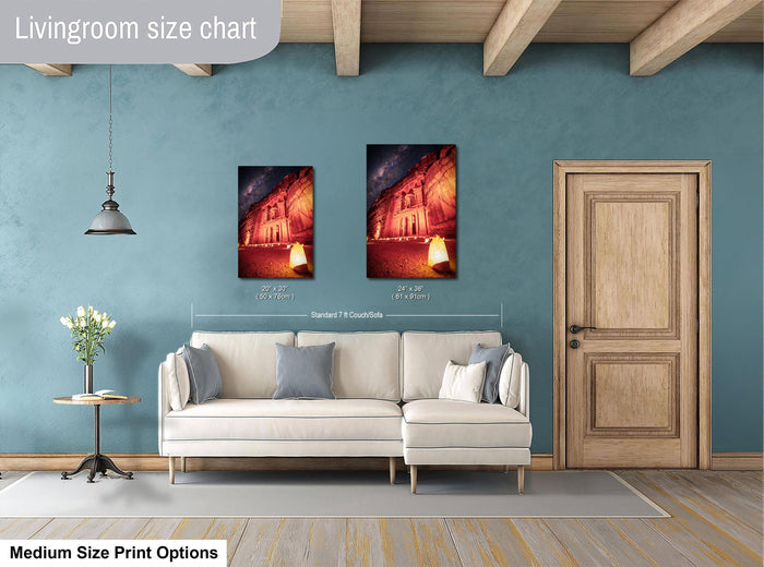 a living room with a white sofa, a wooden door, and a painting of a building on the wall. The painting is of a similar size to the sofa, and the sofa is positioned in front of the painting. The living room appears to be well-lit and decorated with a wooden floor and a lamp hanging from the ceiling.