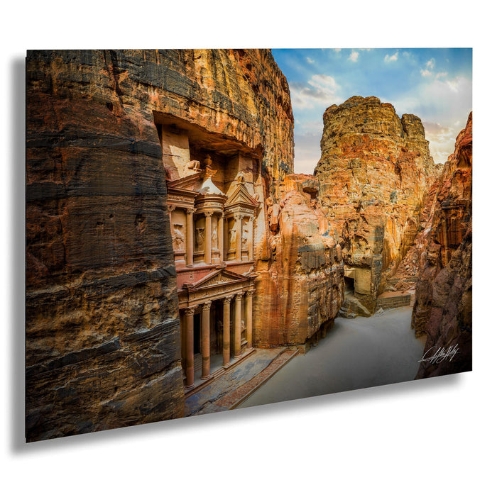 a large, ancient stone structure carved into a cliff face, with a clear blue sky and a river flowing through the landscape.