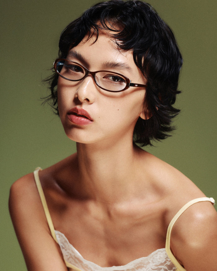 Quarter shot of Bonnie Clyde Pixie optical frames in layered teal demi with clear lenses.