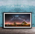 a framed photograph of the pyramids of Giza at night, with the stars visible in the sky above the ancient structures.