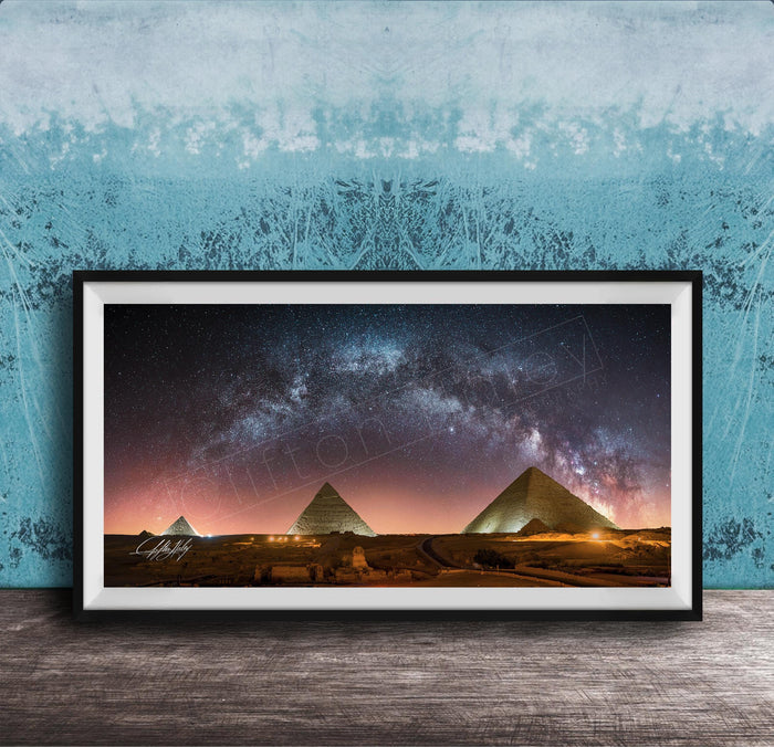 a framed photograph of the pyramids of Giza at night, with the stars visible in the sky above the ancient structures.