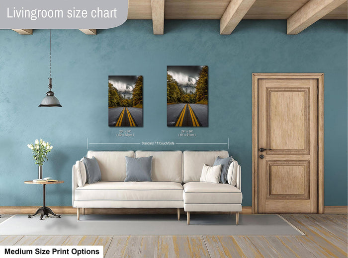 a living room with a white sofa, a wooden door, and a painting of a road with trees on the wall. The painting is of medium size, and the living room appears to be designed for a comfortable and relaxing atmosphere.