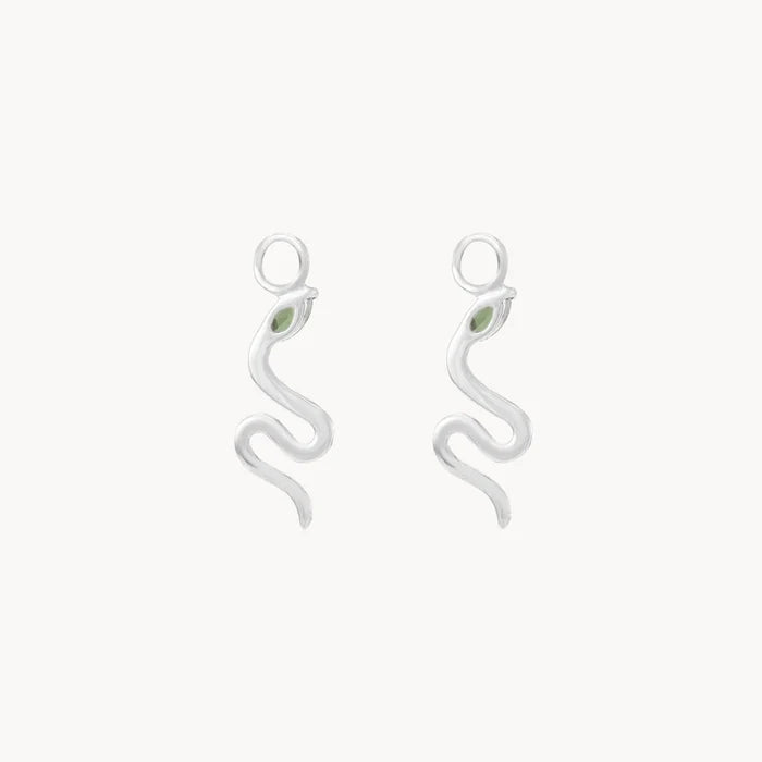 Back view of a pair of silver snake-shaped drop earring charms, each featuring a small marquise green tourmaline gemstone near the head and a smooth silver body, set against a plain off-white background.