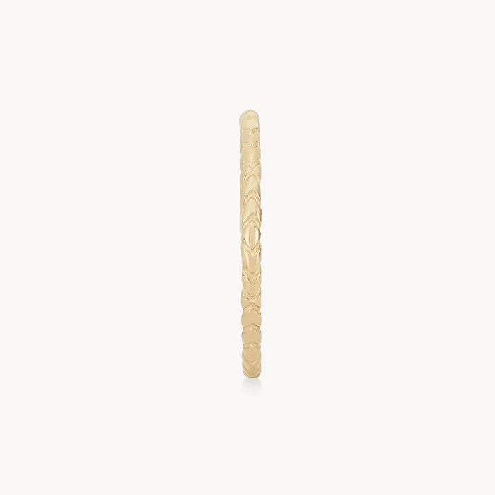 A thin, intricately designed gold ring with a textured pattern visible along its circumference, shown in a vertical orientation against a plain white background. The revival stacking ring - 14k yellow gold by bluboho.