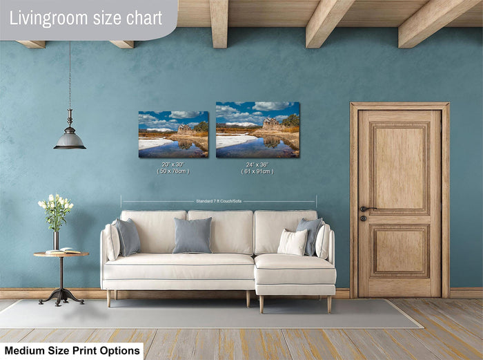 a living room with a white sofa, a wooden door, and a painting of a landscape on the wall. The living room appears to be designed for relaxation and comfort, with a focus on the artwork and the overall aesthetic.