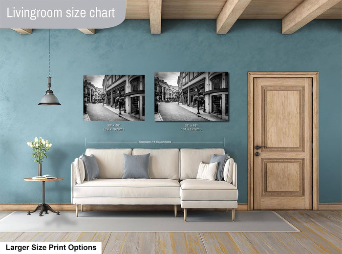 a living room with a white sofa, a wooden door, and a framed black and white photograph of a street scene on the wall.
