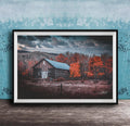 A rustic wooden barn stands in a field, surrounded by trees with vibrant orange leaves against a cloudy sky.