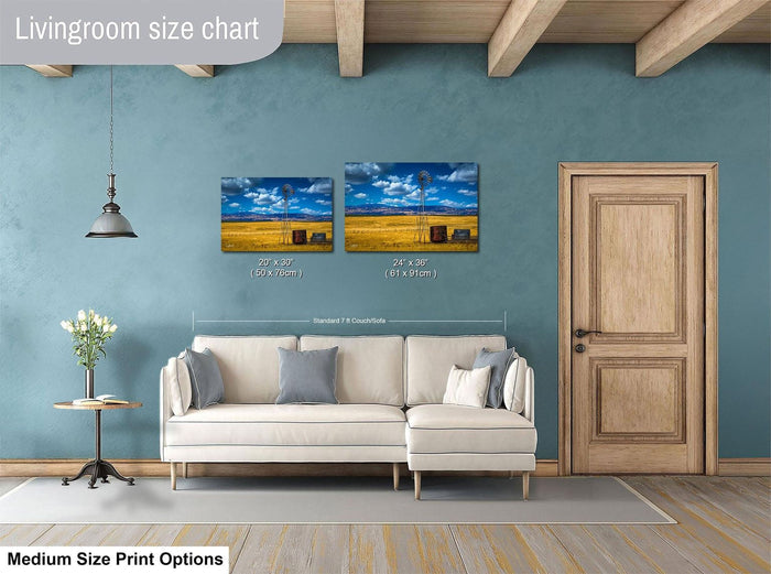 a living room with a white sofa, a wooden door, and two framed landscape paintings hanging on the wall.