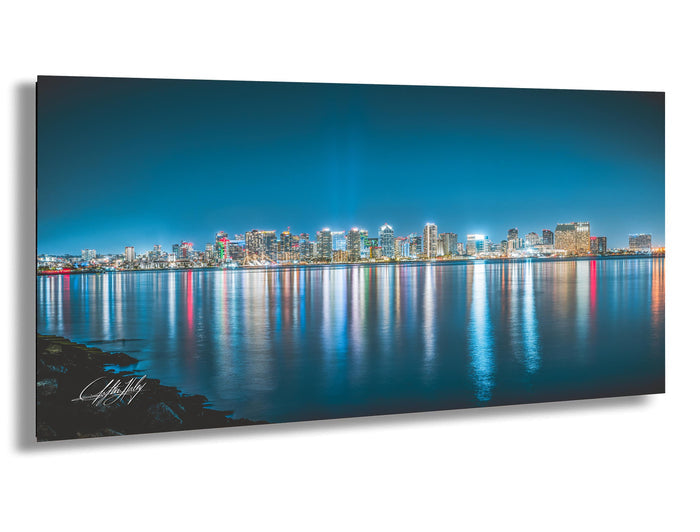 A stunning nighttime cityscape with a skyline of illuminated buildings reflected in the calm waters of a large body of water, creating a mesmerizing and captivating scene.