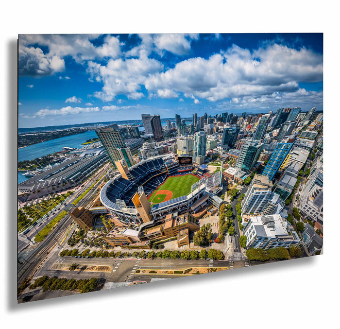 An aerial view of a large baseball stadium surrounded by a cityscape, with tall buildings and a body of water in the background.