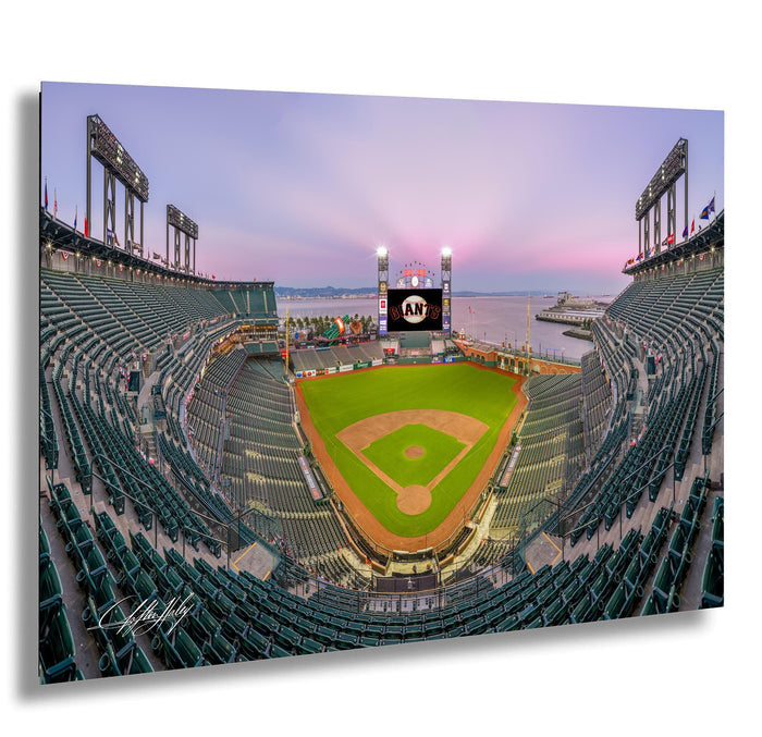A panoramic view of a baseball stadium at dusk, with the field illuminated and the stands filled with spectators.