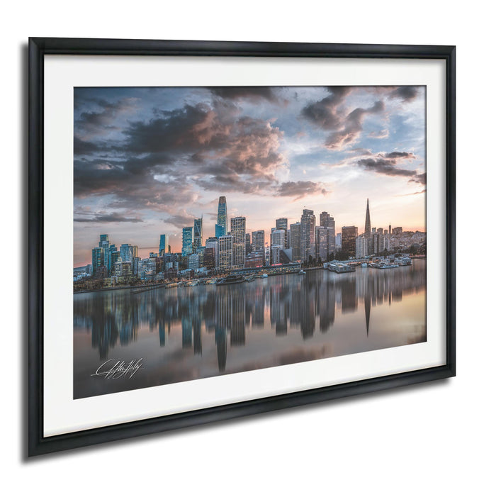 a city skyline at sunset, with the tall buildings reflected in the calm water below.