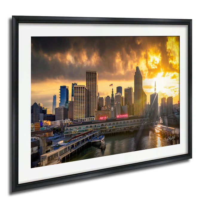 a cityscape with tall buildings and a body of water, possibly a river or bay, during a dramatic sunset.