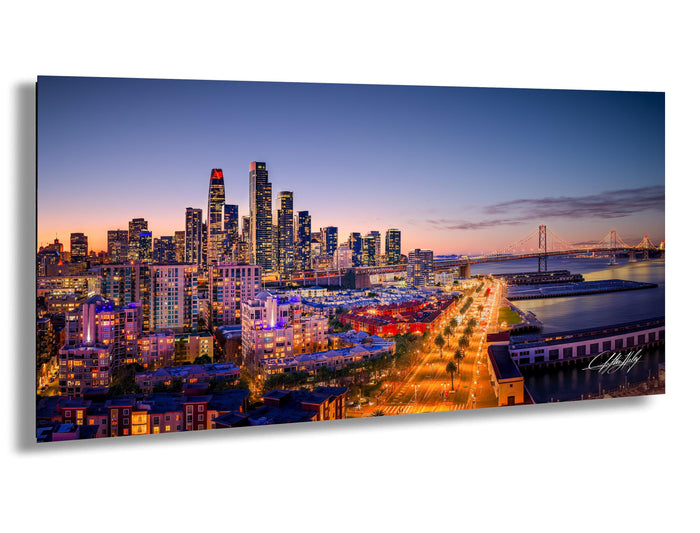 A stunning aerial view of a city skyline at dusk, with the buildings illuminated in vibrant colors against a deep blue sky.