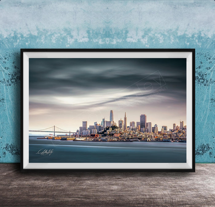 A framed photograph of the San Francisco skyline at sunset, with the Golden Gate Bridge and other iconic structures visible in the distance.