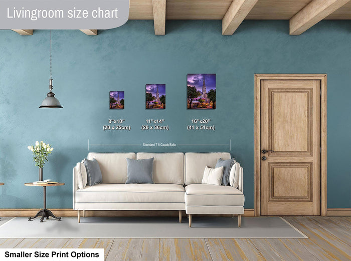 a living room with a white sofa and a wooden door. There are three framed pictures of different sizes displayed on the wall above the sofa.