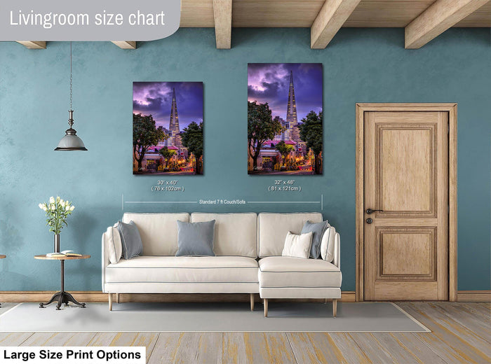 a living room with a white sofa and a wooden door. There are two framed pictures hanging on the wall, depicting a cityscape with a tall building. The living room appears to be well-decorated and spacious.