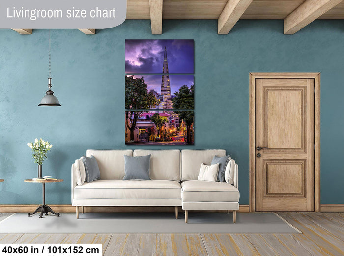 The image is a living room with a large, colorful painting of a cityscape hanging on the wall. The painting features a tall tower and a scenic view of the city. The room has a white sofa, a wooden door, and a small table with a vase of flowers. The living room size chart indicates that the painting is 40 inches by 101.152 centimeters wide.