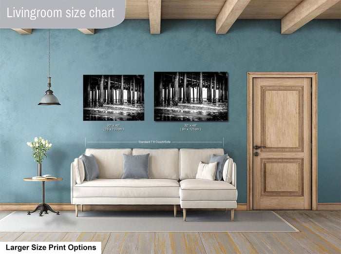 a living room with a white sofa, a wooden door, and two framed black and white photographs hanging on the wall.