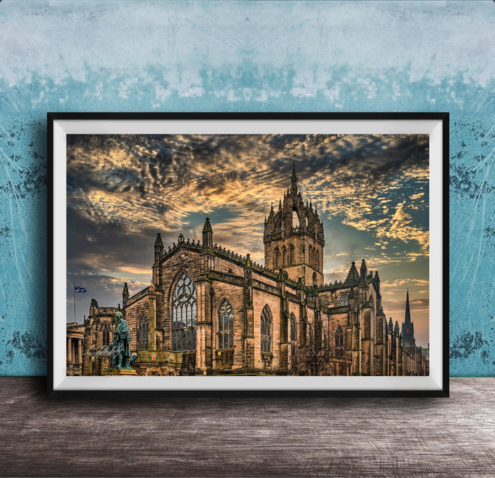 A framed photograph of a large, ornate cathedral with a castle-like structure, set against a dramatic sky with clouds and a sunset.
