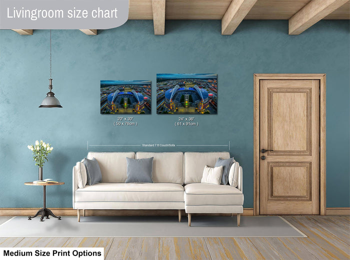 a living room with a white sofa, a wooden door, and a painting of a cityscape on the wall. The painting is of a stadium, and the sofa is positioned in front of it. The living room appears to be well-lit and decorated with a potted plant and a vase.