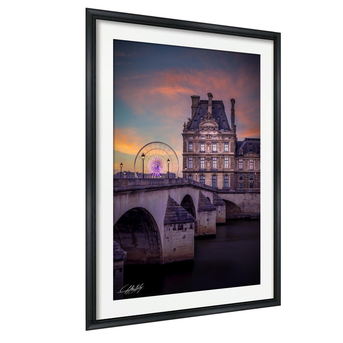 a picturesque scene of a historic building with a large, ornate dome, set against a vibrant sunset sky. In the background, a Ferris wheel can be seen, adding a whimsical touch to the scene. The photograph is framed and appears to be a piece of art, showcasing the beauty of the landmark and its surroundings.