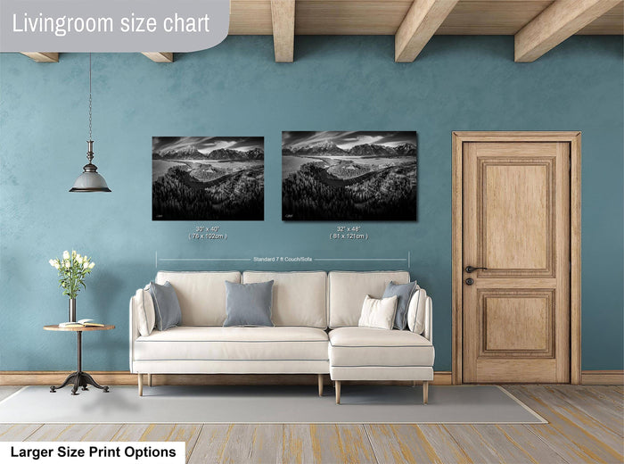 a living room with a white sofa, a wooden door, and two framed landscape photographs hanging on the wall.