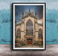 A framed photograph of a Gothic cathedral with a large rose window and a tall spire, set against a cloudy sky.