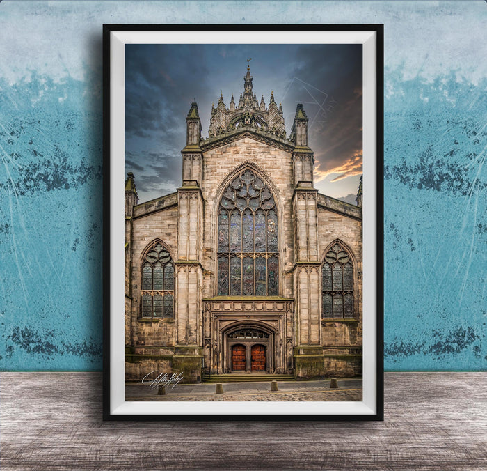 A framed photograph of a Gothic cathedral with a large rose window and a tall spire, set against a cloudy sky.