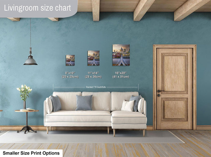 a living room with a white sofa, a wooden door, and a hanging light fixture. There are three framed artworks displayed on the wall, each with a different size and frame. The living room appears to be well-decorated and spacious.