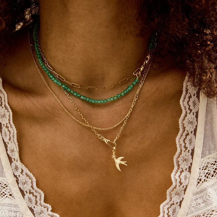 Starbound Swallow Bird Charm in 10k yellow gold with brilliant diamond, shown worn on hand