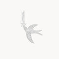 Front view of a silver pendant shaped like a flying swallow holding a five-pointed star, with a small clear stone set in the center of the star, shown on a plain off-white background.
