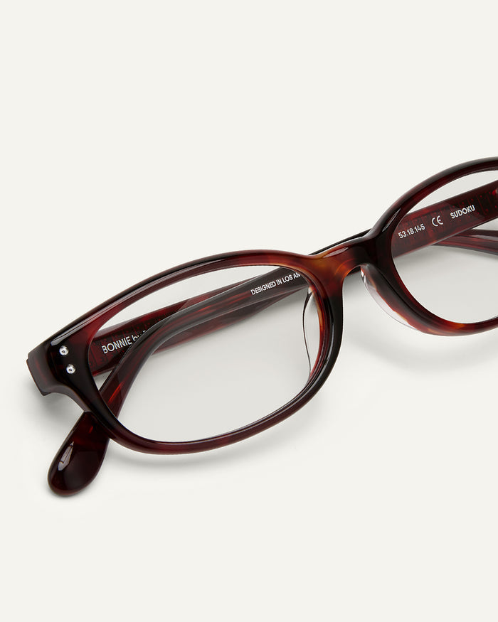 Close-up shot of Bonnie Clyde Sudoku optical frames in red tortoise with clear lenses.