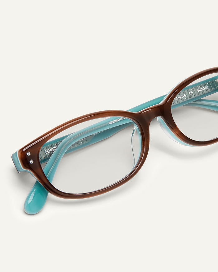 Detail shot of Bonnie Clyde Sudoku optical frames in layered teal demi with clear lenses.