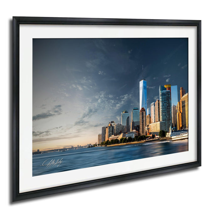 A framed photograph of the New York City skyline, with the One World Trade Center prominently visible against a cloudy sky.