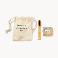 A sustainable non-toxic cleaning kit from bluboho, featuring a small drawstring bag labeled "sustainable non toxic cleaning kit" and "bluboho," a wooden brush with dark bristles, and a bar of soap wrapped in paper with a decorative label. The items are arranged neatly on a white background.
