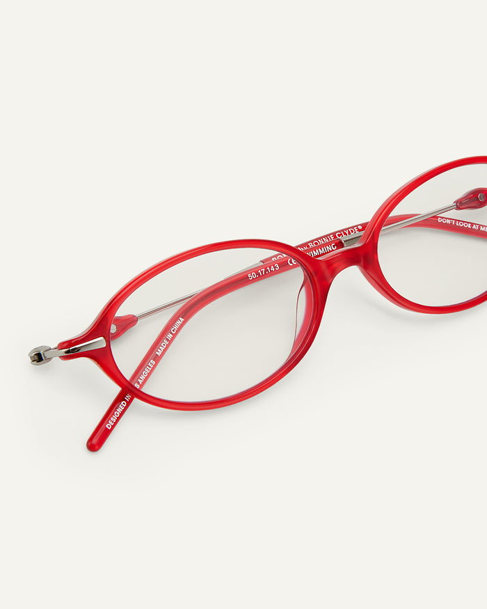 Close-up shot of Bonnie Clyde Swimming optical frames in silver and layered red with clear lenses.