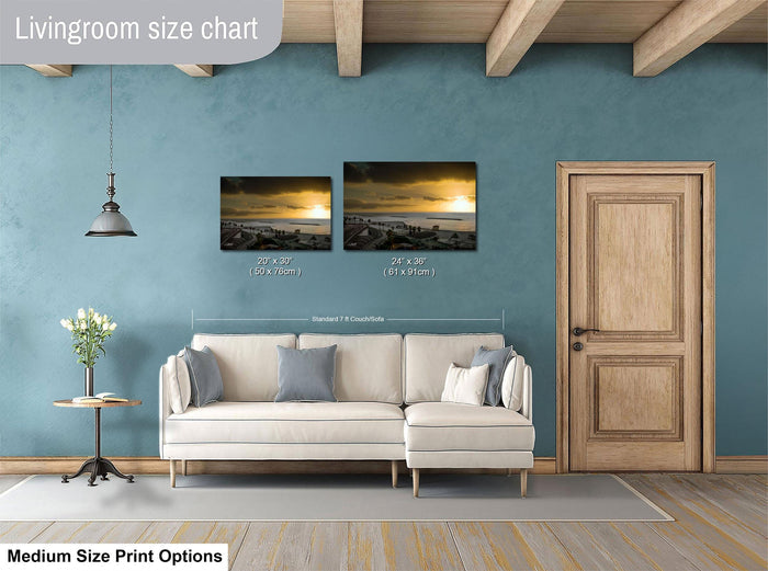 a living room with a white sofa, a wooden door, and a painting of a sunset on the wall. The painting is of medium size, and the sofa is of standard size. The living room appears to be well-decorated with a potted plant and a vase.