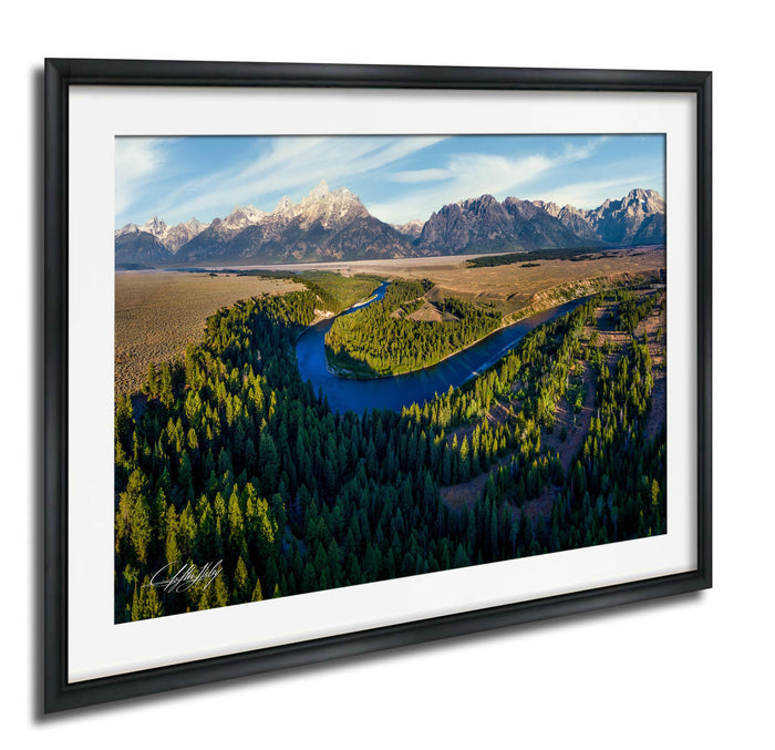 a serene landscape with a winding river surrounded by lush green forests and majestic snow-capped mountains in the background.