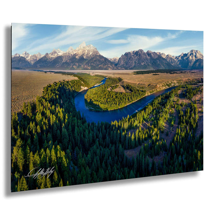 a serene landscape with a winding river surrounded by lush green forests and majestic snow-capped mountains in the background.