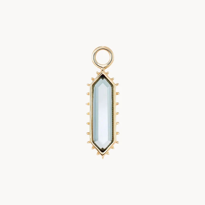 A front view of an elongated hexagon earring charm with a london blue topaz stone surrounded by spiked edges, shown on a plain off-white background.