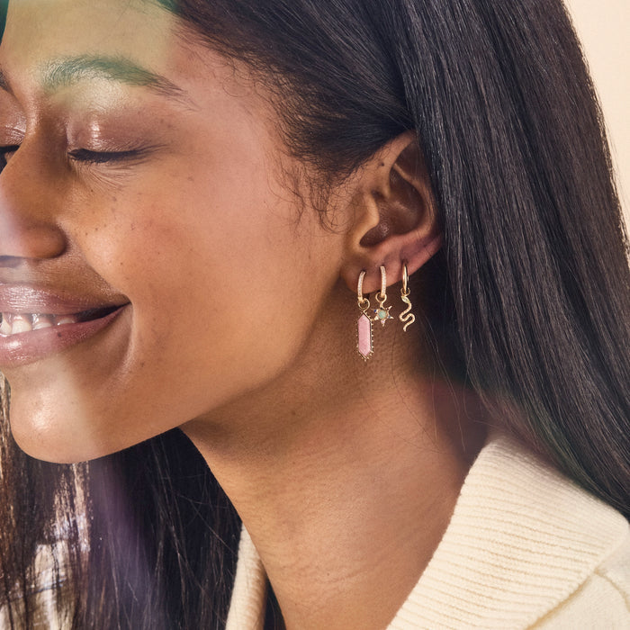 The Goddess Rhodochrosite Earring Charm in 10k yellow gold with rhodochrosite gemstone, shown worn on hand