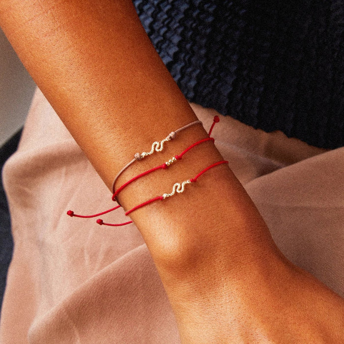 The Serpent Contemplation Cord Bracelet in 10k yellow gold with red cord, alternate angle detail view