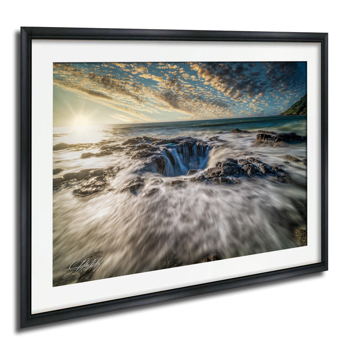 A framed photograph depicting a dramatic waterfall cascading into a deep crevasse, with a stunning sunset sky in the background.