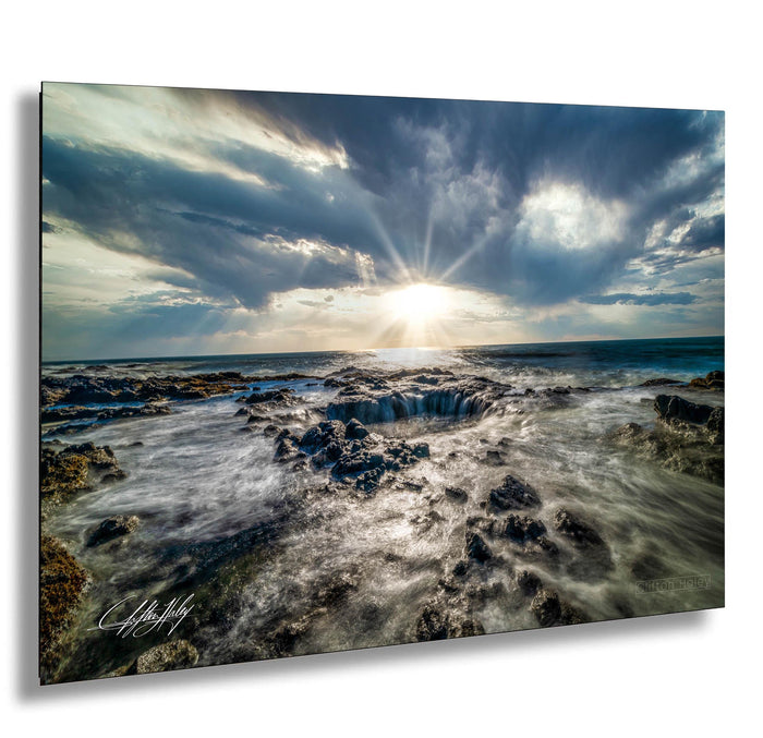 a rocky coastline with crashing waves, a bright sun shining through the clouds, and a dramatic sky.