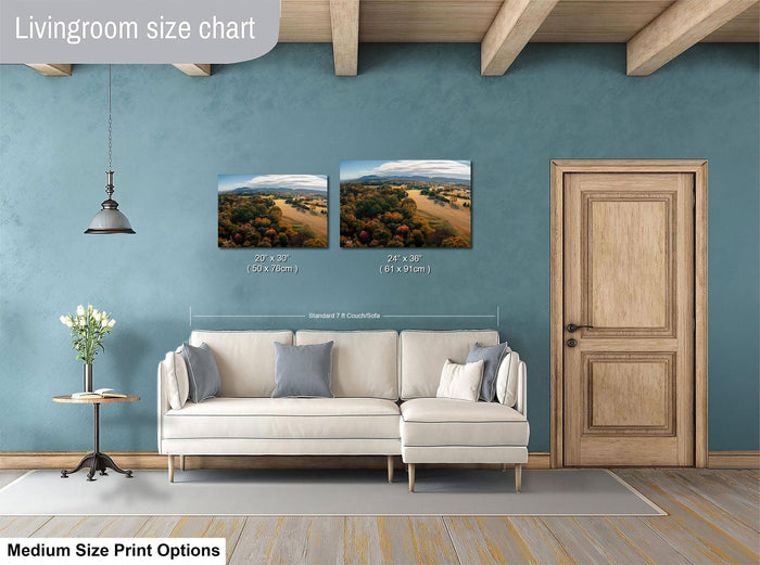 a living room with a white sofa, a wooden door, and a painting of a landscape on the wall. The painting is of medium size, and the living room appears to be designed for a comfortable and relaxing atmosphere.